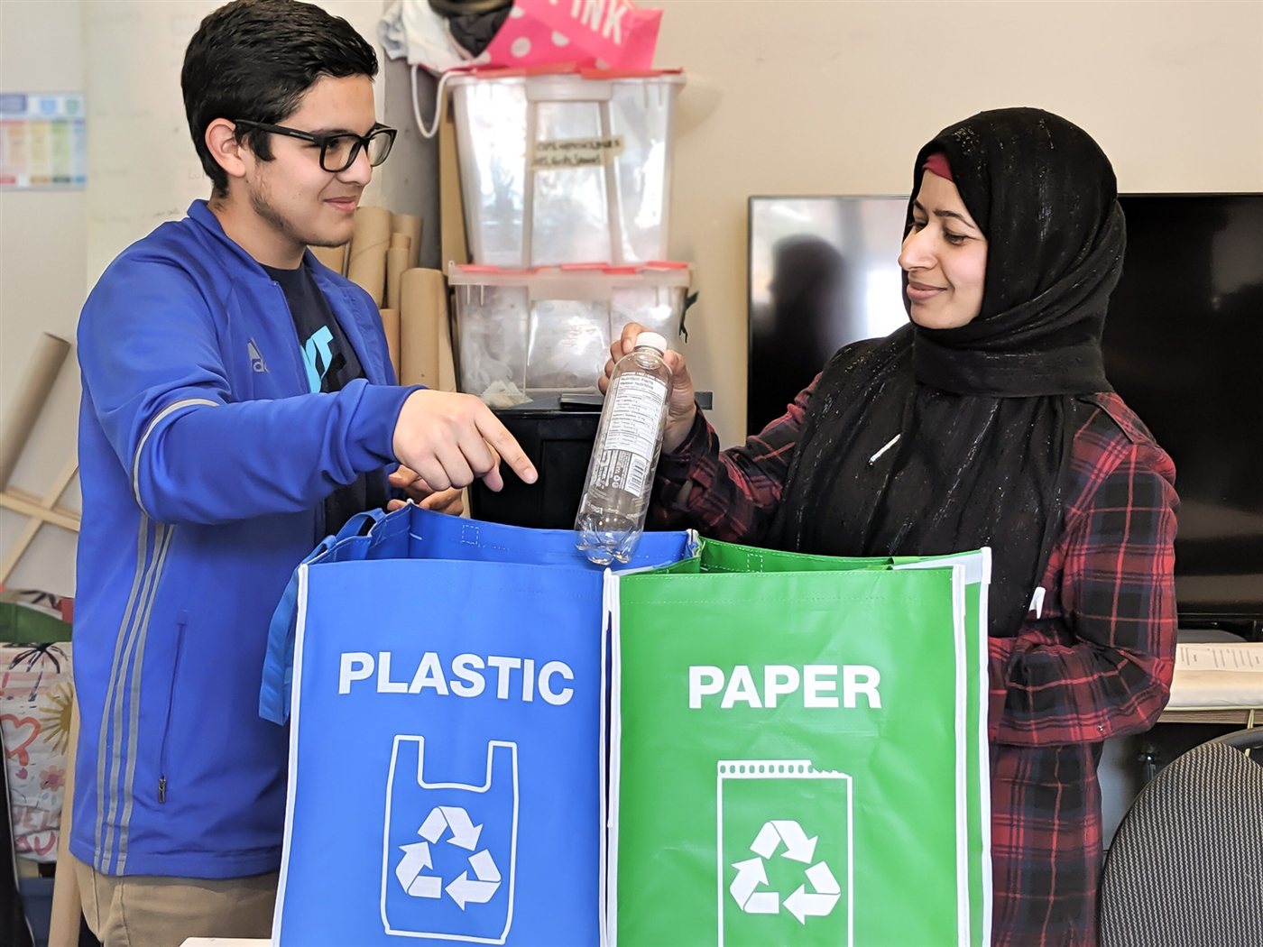 Daniel showing an adult learner how to sort recycling