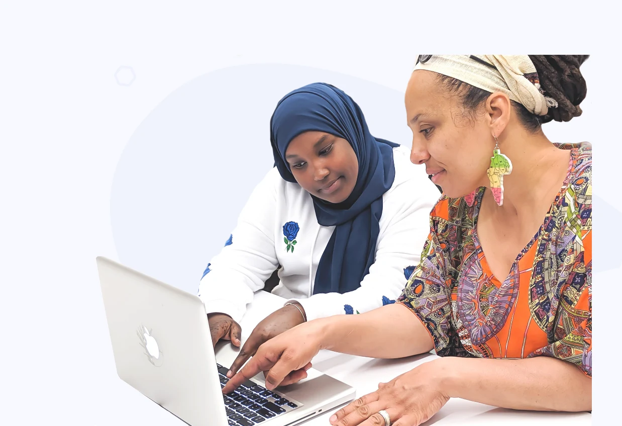 A youth tutor and an adult learner working together on a laptop